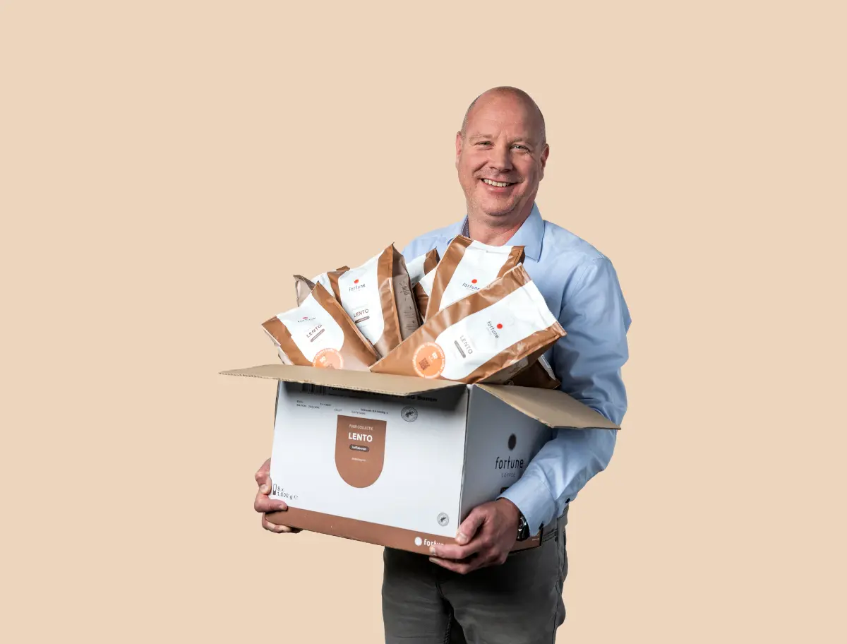 Medewerker regio Valkenswaard heeft een doos met zakken met koffiebonen in z'n hand